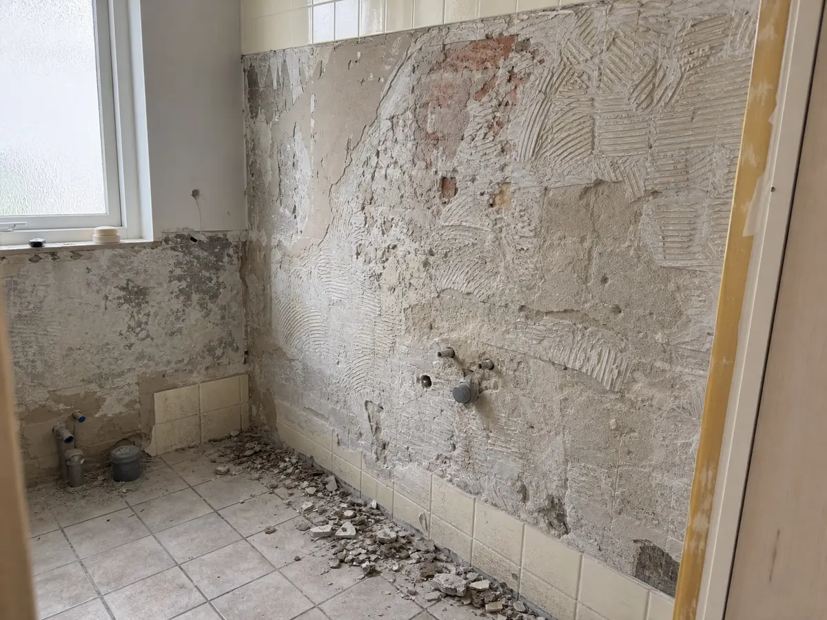 Ældre badeværelse under renovering, hvor de gamle fliser er taget ned
